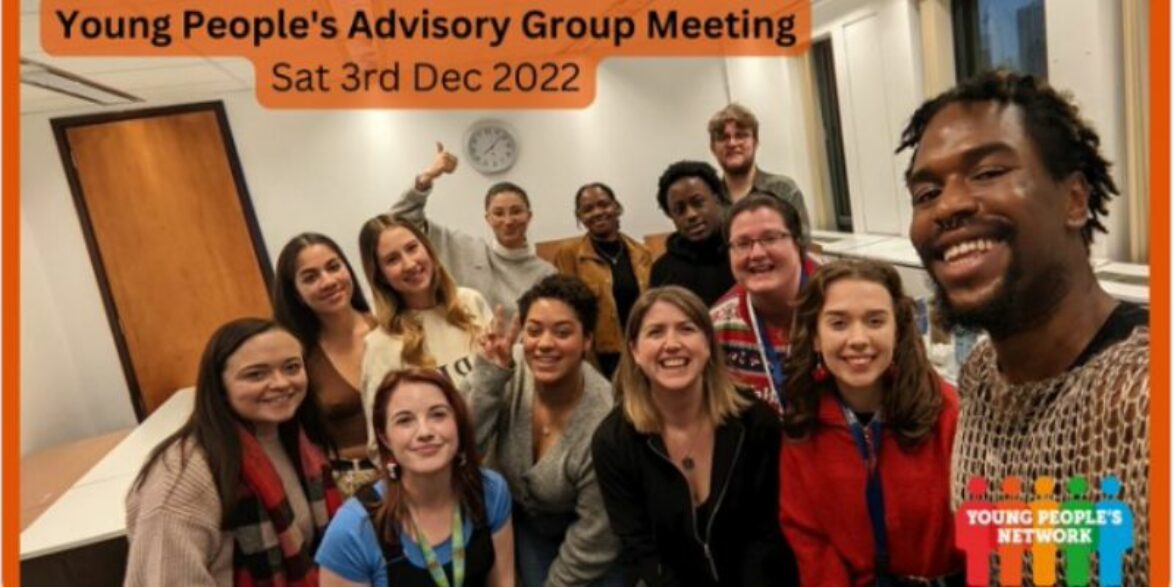 A selfie of a group of thirteen young people from the McPin Young People's Advisory Group standing in a meeting room. Everyone is smiling.
