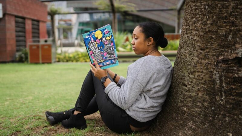 Young woman sitting in a park reading a book